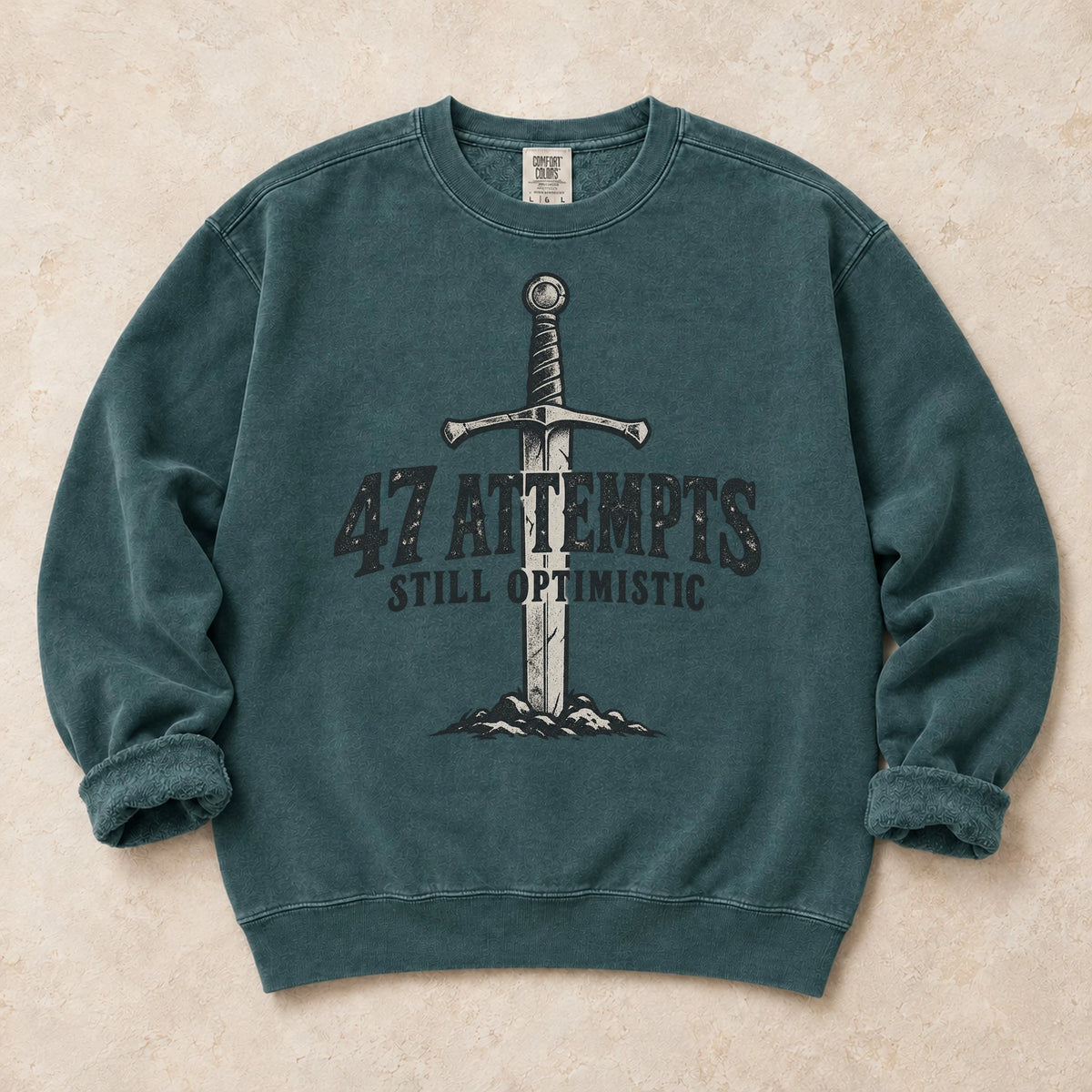 Blue Spruce gaming sweatshirt. A planted sword celebrates 47 attempts and still optimistic.