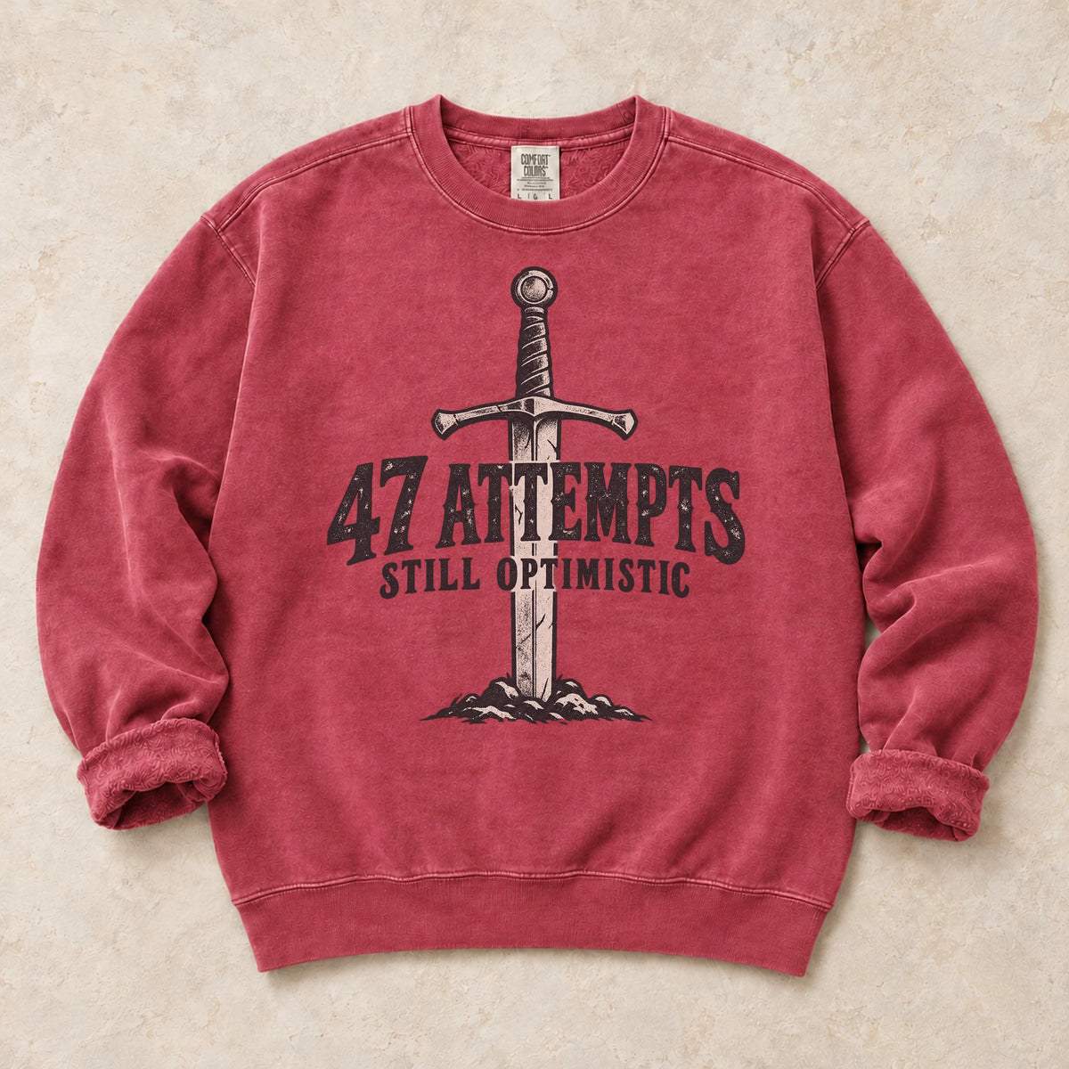 Crimson gaming sweatshirt. A planted sword celebrates 47 attempts and still optimistic.