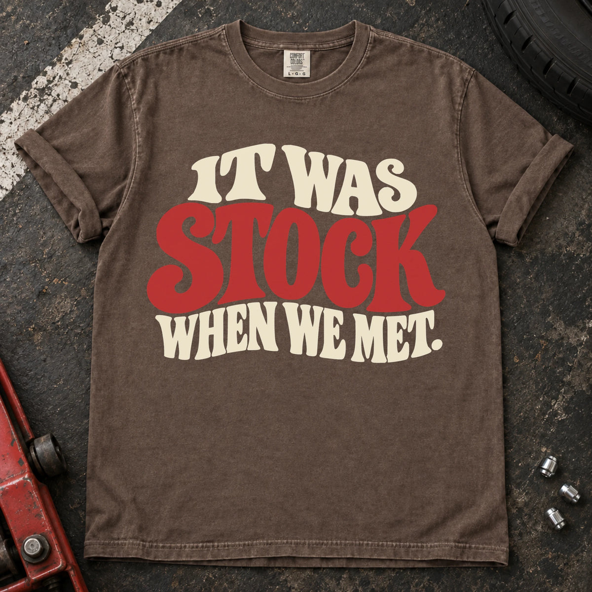 Espresso T-shirt with cream and red vintage lettering reading 'It was stock when we met'.