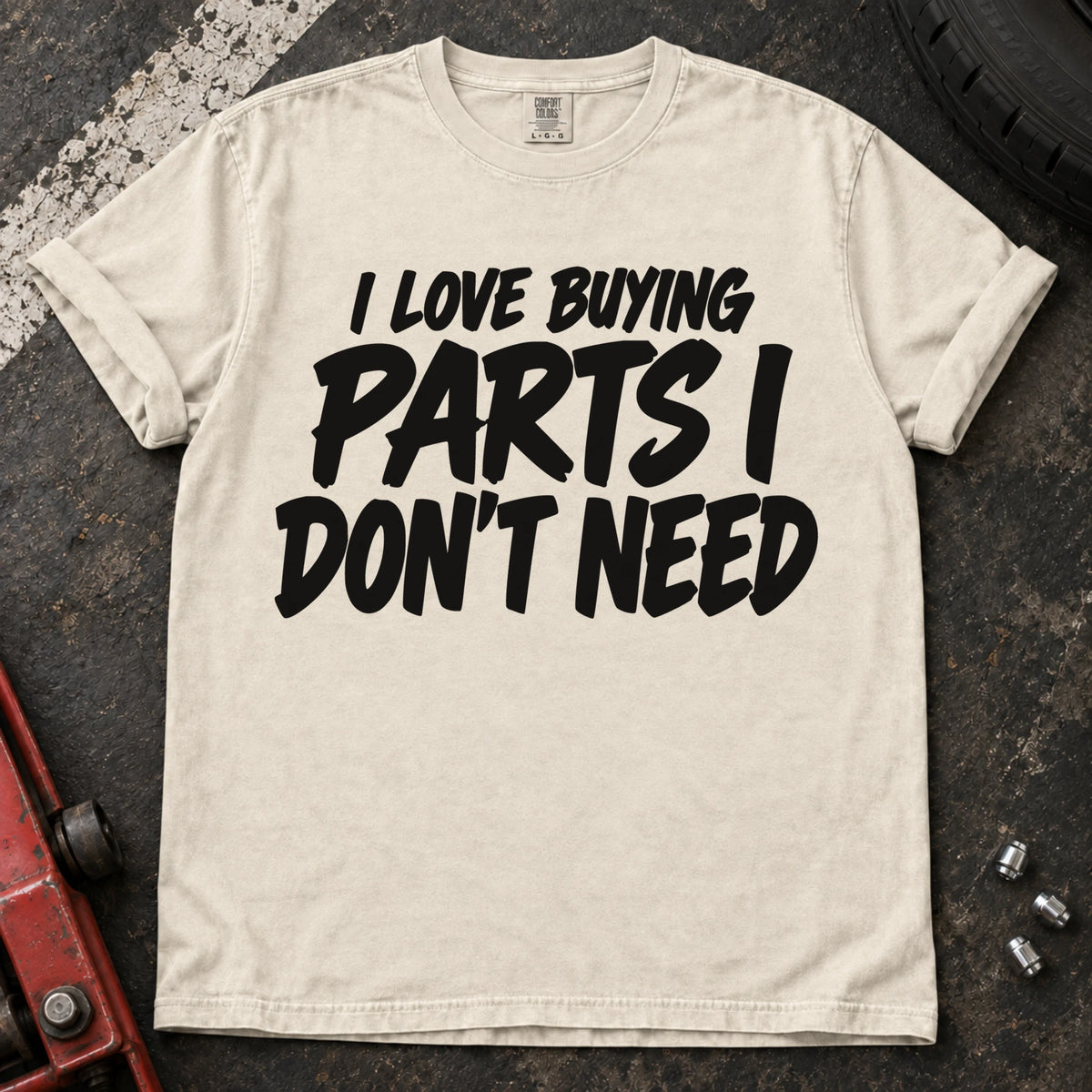 Ivory T-shirt with bold black lettering reading 'I love buying parts I don't need'.