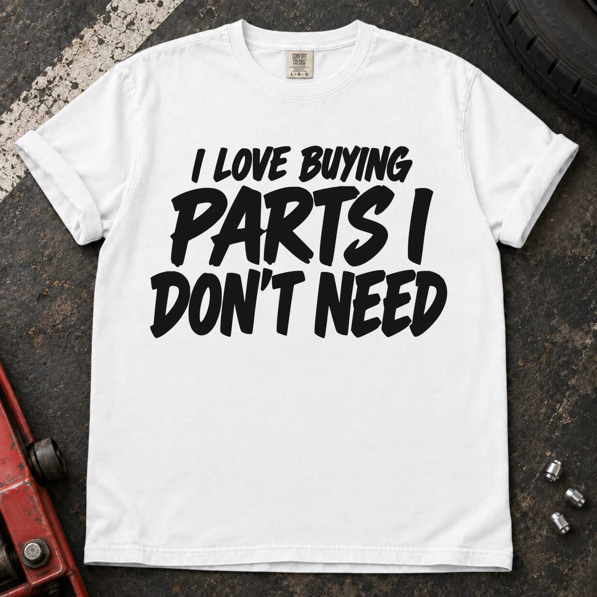 White T-shirt with bold black lettering reading 'I love buying parts I don't need'.