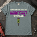 Bay T-shirt showing a coilover beneath 'Very serious about an unnecessary upgrade' in cream and purple lettering.