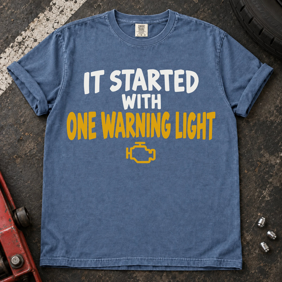 Blue Jean T-shirt reading 'It started with one warning light' above a check-engine symbol.