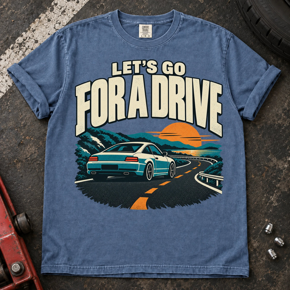 Blue Jean car enthusiast T-shirt. A car cruises a sunset mountain road under let's go for a drive.